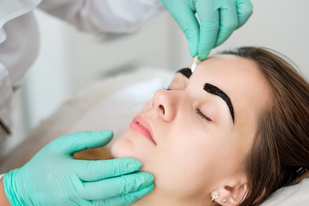 Beautician removing eyebrow tint